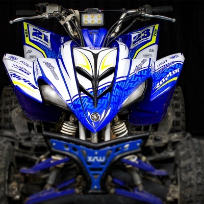 Quadriciclo azul e branco visto de frente com pneus grandes em fundo negro