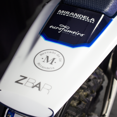 Área traseira de motorizada branca com texto e assento azul perfurado