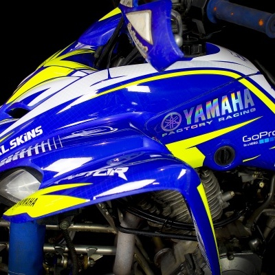 Parte lateral de veículo Yamaha azul com detalhes amarelos e brancos e vários logótipos