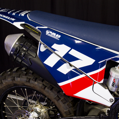 Parte traseira de mota off-road azul, branca e vermelha com número 17 e logos