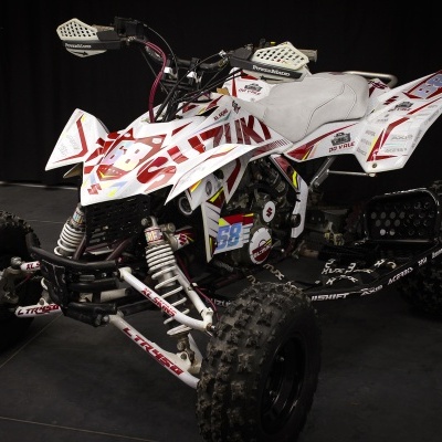 Quadriciclo branco e preto com autocolantes vermelhas e assento cinzento