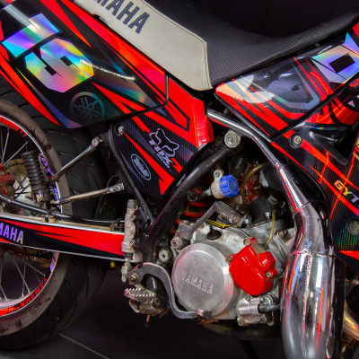 Motociclo Yamaha vermelha e preta com números 19 e 02 e motor exposto
