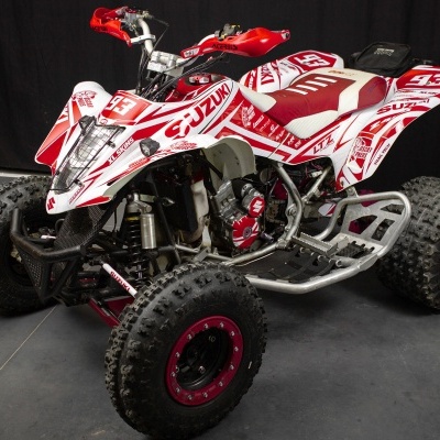 Quadriciclo Suzuki branco e vermelho com pneus de borracha texturizada para off-road