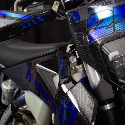 Motocicleta Husqvarna preta e azul com número 25 e farol angular