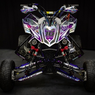 Quadriciclo branco, roxo e preto com número 10 na frente e pneus robustos