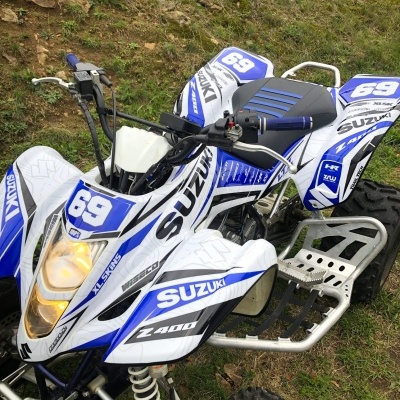 Quad Suzuki Z400 branco e azul com número 69 em área de relva e terra
