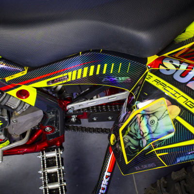 Parte lateral de mota Suzuki com grafismo colorido e texto visível