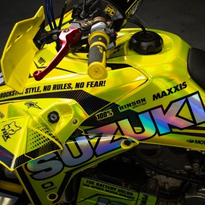 Motociclo Suzuki amarelo com texto colorido e marcas visíveis