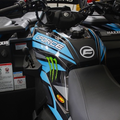 Quadriciclo preto com detalhes azuis e verdes e etiquetas visíveis