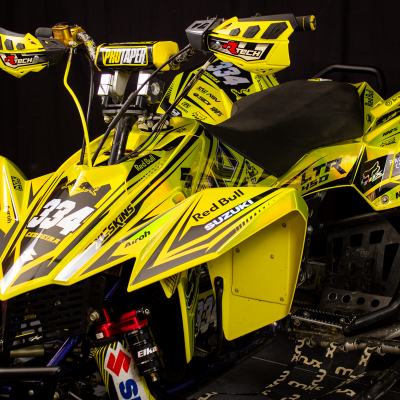 Quad amarelo com número 934 e várias marcas, sobre fundo preto