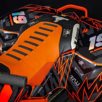 Quadriciclo laranja e preto com assento texturizado e números 19 e R. BARROSO visíveis.