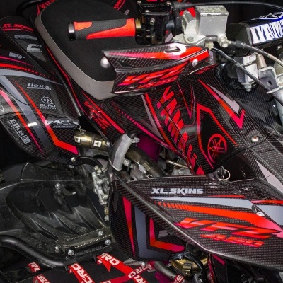 Veículo todo-o-terreno preto e vermelho com detalhes de fibra de carbono e texto XL-SKINS.
