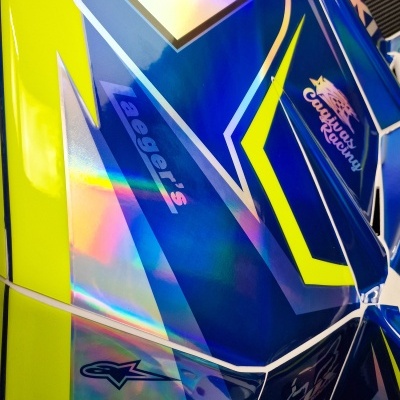 Parte lateral de mota de corrida azul e amarela com números e adesivos holográficos