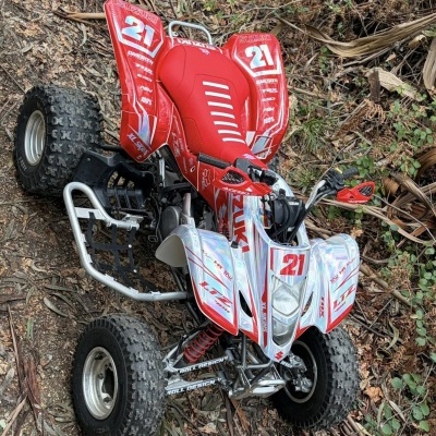 Quad Suzuki LTZ 400 vermelho e branco com pneus grossos para terrenos off-road em ambiente natural