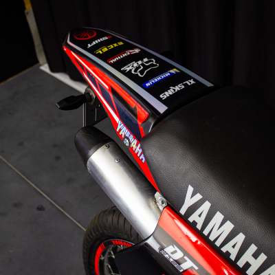 Moto Yamaha vermelha e preta com banco preto e textos no para-lama traseiro