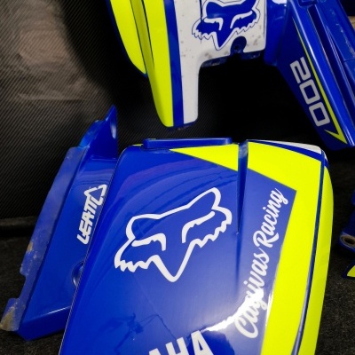 Peças plásticas para mota Yamaha com logos Fox Racing e texto ASV 200, em azul e amarelo