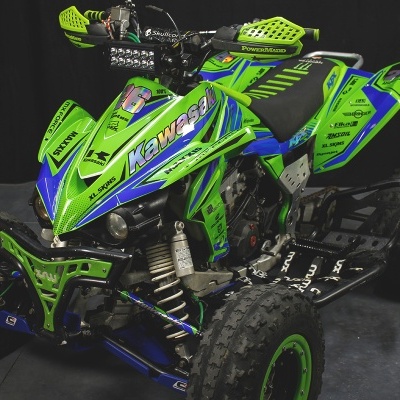 Quad todo-o-terreno verde e azul com pneus grandes e proteções de guiador verdes