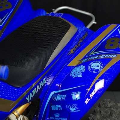 Parte traseira de mota Yamaha azul com detalhes dourados e preto, com vários textos e logos