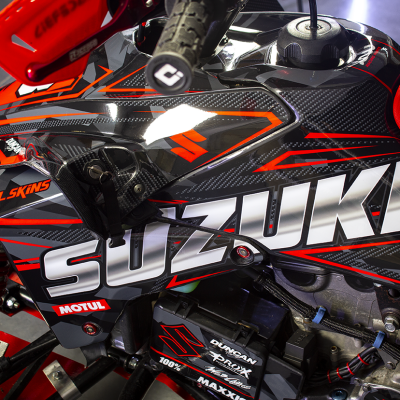 Parte lateral de veículo motorizado com adesivos e assento vermelho