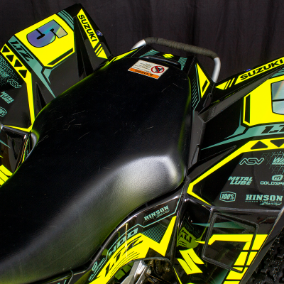 Veículo ATV Suzuki amarelo e preto com assento preto e várias inscrições visíveis
