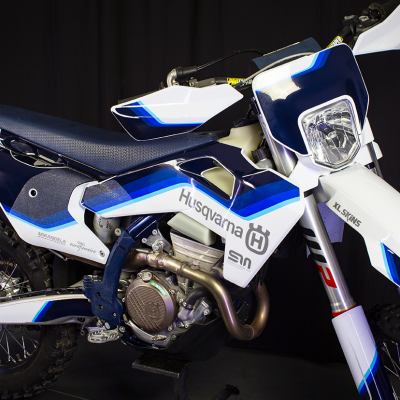 Motocross Husqvarna azul e branco com pneus de lama e farol quadrado