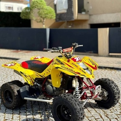 Quadriciclo amarelo Suzuki com pneus grandes e número 21 em calçada de pedras