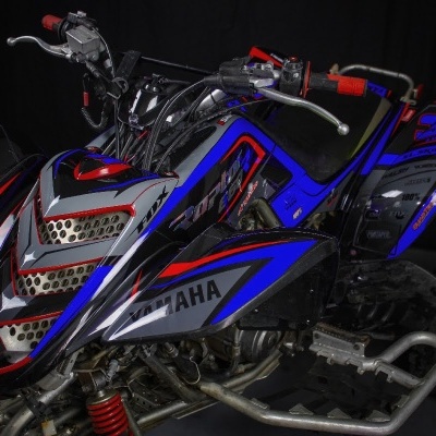 Quad Yamaha azul, vermelho e cinza com número 31 na traseira e pneus com textura de lama