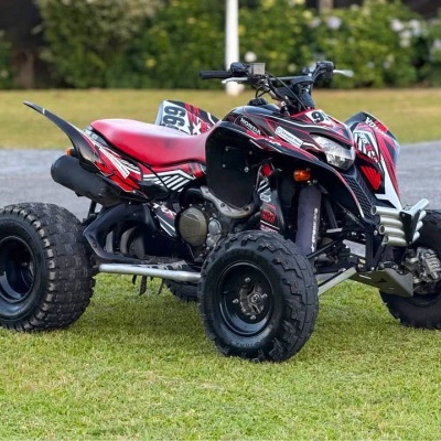 Quadriciclo preto e vermelho com número 99, pneus largos, sobre relva verde