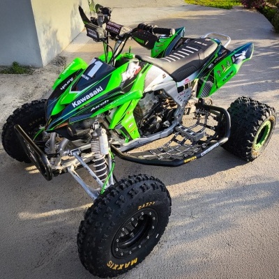 Quadriciclo Kawasaki verde e preto com pneus Maxxis em pavimento