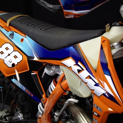 Motocross KTM laranja e azul com número 88 e assento preto