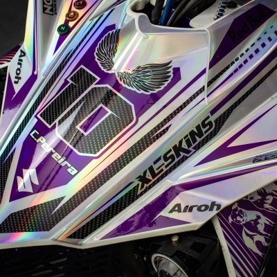 Detalhe da parte frontal de veículo de corrida com cores branco, roxo e preto e textos 10 XL5SKINS Airoh