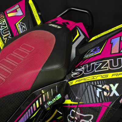 Assento de mota de corrida vermelho e preto com decorações coloridas e textos em rosa, amarelo e preto