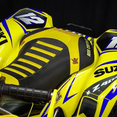 Assento e parte do guiador de um quad Suzuki amarelo com detalhes em azul e preto