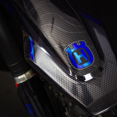 Guarda-lamas de mota em carbono com símbolo azul HUSQVARNA e detalhes azuis iluminados