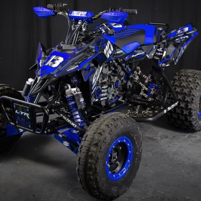 Quadriciclo Suzuki LTR azul e preto com pneus Maxxis num fundo escuro