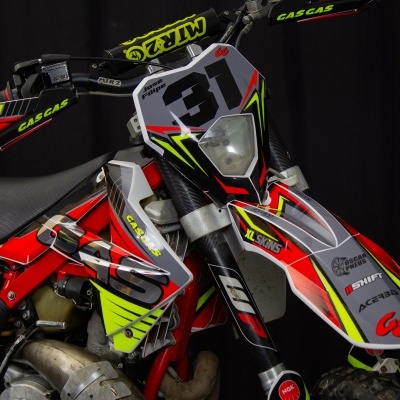 Motociclo de competição vermelho, branco, amarelo e preto com número 31 e proteções verdes CASCAS