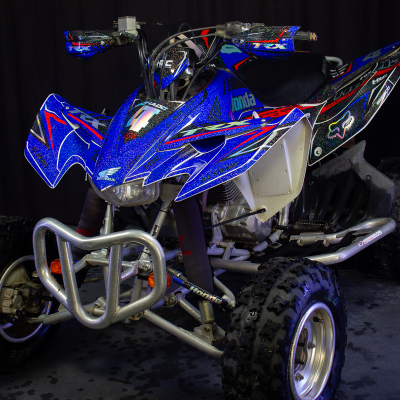 Quad Honda azul e preto com detalhes gráficos e pneus de terra