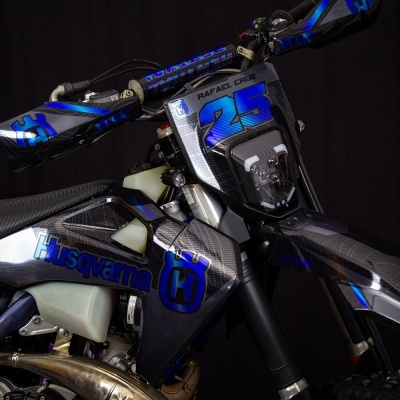 Motociclo Husqvarna preto e azul com número 25 e textura fibra de carbono