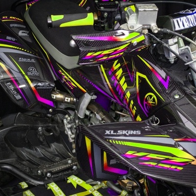 Quad preto com detalhes coloridos em rosa, amarelo e verde com acabamentos de carbono e pneus de borracha