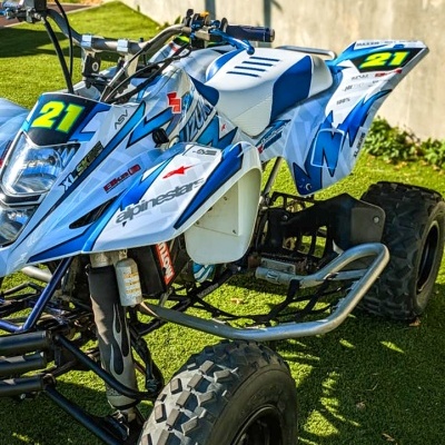 Quadriciclo desportivo branco e azul com detalhes amarelos e pneus largos