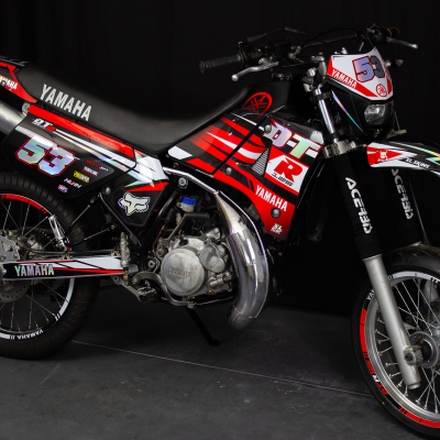 Motocross Yamaha preta e vermelha com número 53 em fundo escuro