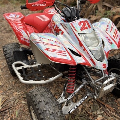 Quad Suzuki com grafismos vermelhos e holográficos, proteção ACEBIS e pneus off-road