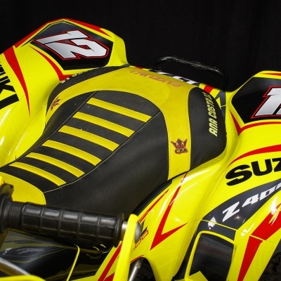 Veículo todo-o-terreno amarelo e preto com números 12 e logótipos SUZUKI em detalhe.