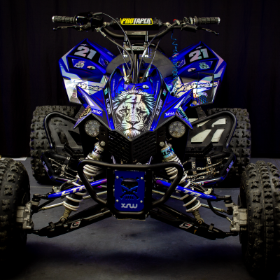 Quadriciclo azul e preto com gráficos de tigre e número 21 em fundo escuro