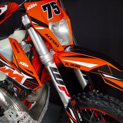 Moto de motocross KTM laranja, preto e branco com o número 75 e autocolantes em fundo preto
