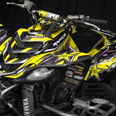 Quadriciclo Yamaha preto e amarelo com capacete correspondente e várias insígnias visíveis