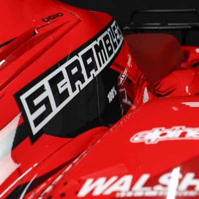 Carro de corrida vermelho com vários logos de patrocinadores