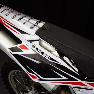 Assento de mota de cross preto com detalhes vermelhos e brancos e número 53 na parte traseira