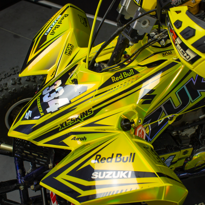 Veículo todo-o-terreno amarelo Suzuki com texto Red Bull, XP SKINS, AIROH e número 44