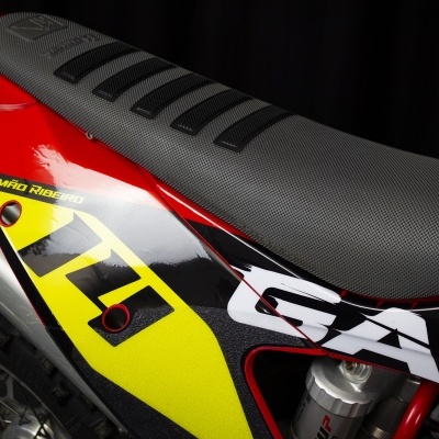 Detalhe do assento e grafismo de mota com texto SIMÃO RIBEIRO e GAS